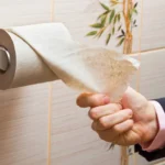 Hand of a businessman reaching for toilet paper