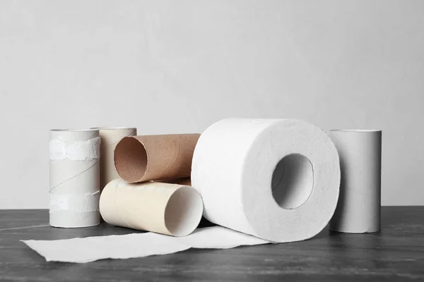 Full and empty toilet paper rolls on table against grey background