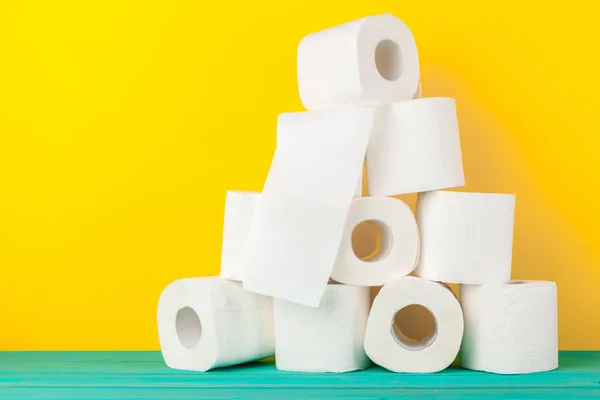 Toilet paper rolls stacked against yellow paper background