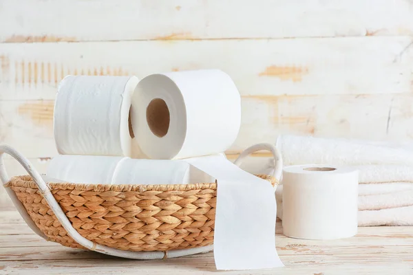 Basket with toilet paper on wooden background