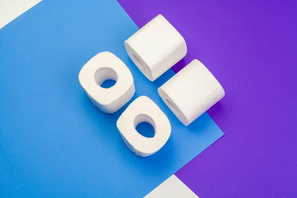 Rolls of unfolded toilet paper on a blue background.