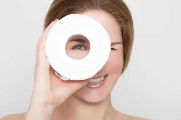 Beautiful woman looks through a roll of toilet paper