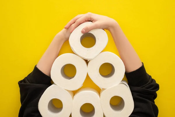 Cropped view of woman grabbing white toilet paper rolls arranged in pyramid