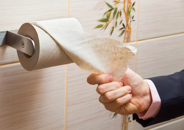 Hand of a businessman reaching for toilet paper