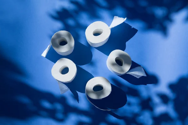 Toilet paper on a blue background with shadows of trees