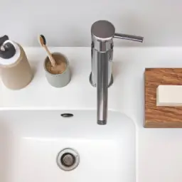 An image showcasing a minimalist bathroom countertop adorned with reusable, bamboo toothbrushes, refillable soap dispensers, a sleek compost bin, and recycled toilet paper—all immersed in a soft, natural color palette